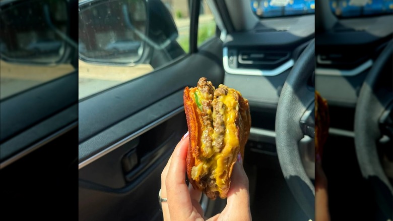 A hand holds up a cross-section of a Five Guys patty melt with two burger patties