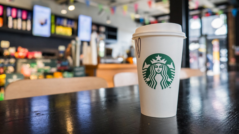 A Starbucks cup with a heart drawn on the side on a counter inside its cafe