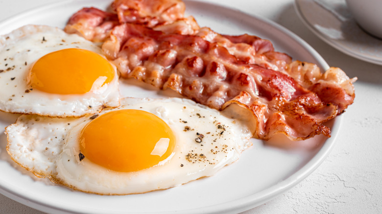 Fried eggs with bacon on a white plate