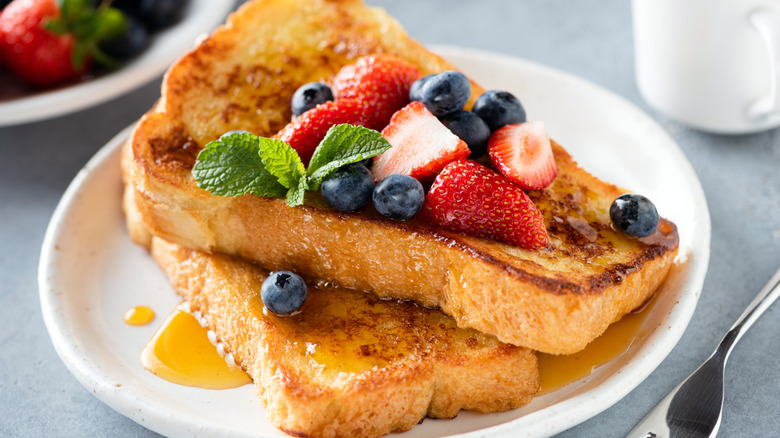 French toast topped with syrup and fresh berries on a white plate