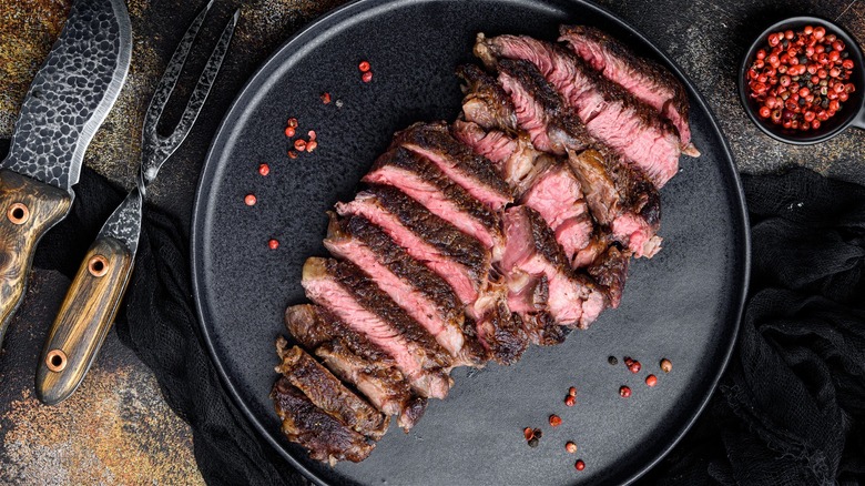 sliced steak on plate with knife and fork