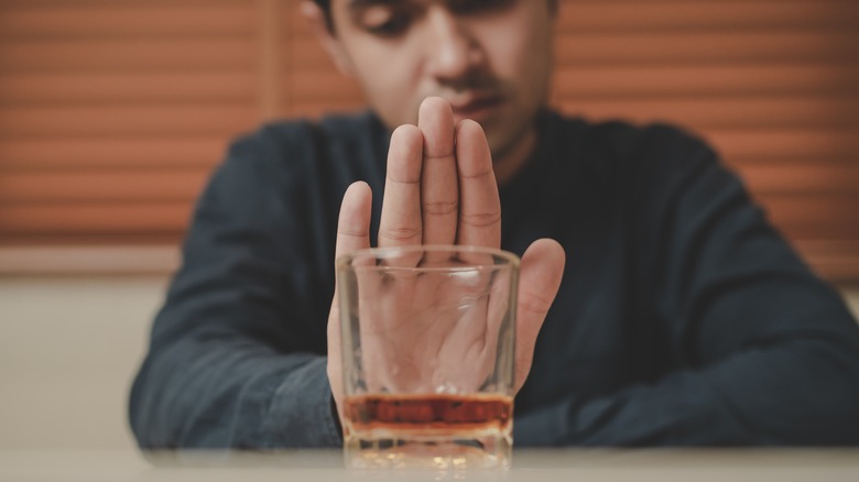 Man pushing away whiskey glass 
