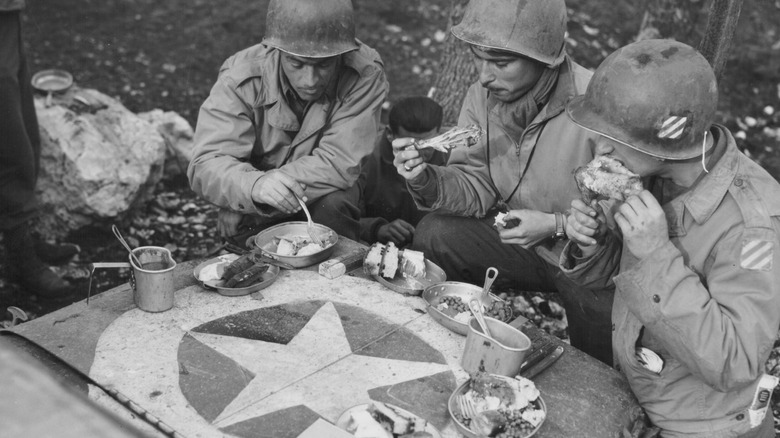 WWII American soldiers eating dinner on hood of jeep