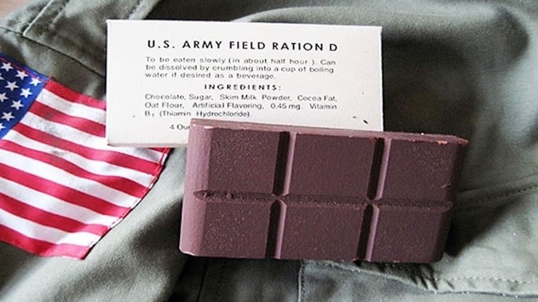 A field ration D chocolate bar with its ingredients card and a tiny American flag lying on a military uniform