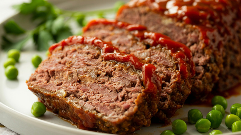 Slices of meatloaf on a plate with with peas