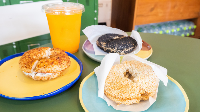 Toasted sesame bagel with cream cheese on plate with orange juice