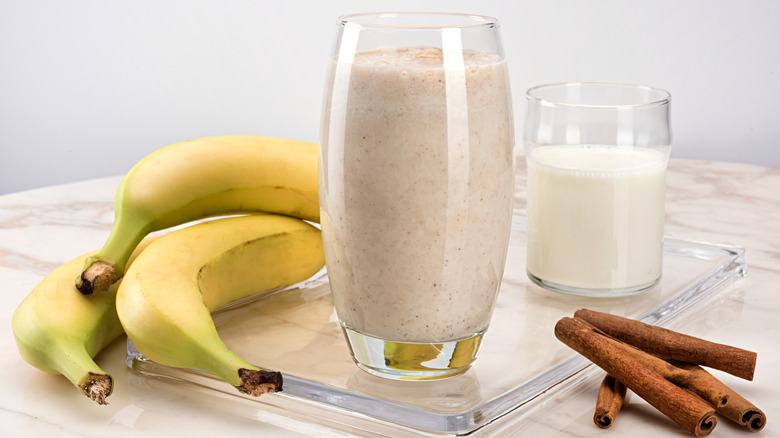Bananas beside a banana milkshake in a glass