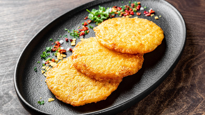 Potato hash browns with garnish on black plate