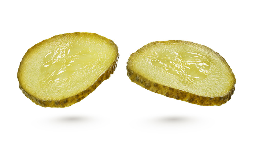 Two sliced pickles on a white background