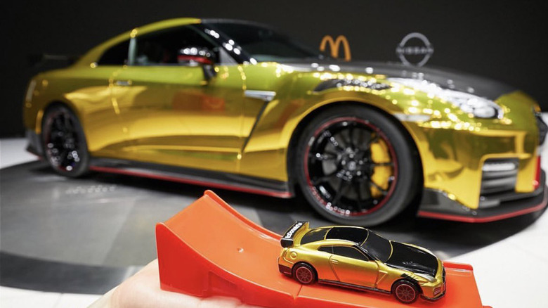 Holding a McDonald's toy GT-R in front of the McDT-R