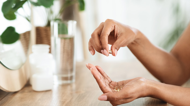 Person taking supplement with glass of water