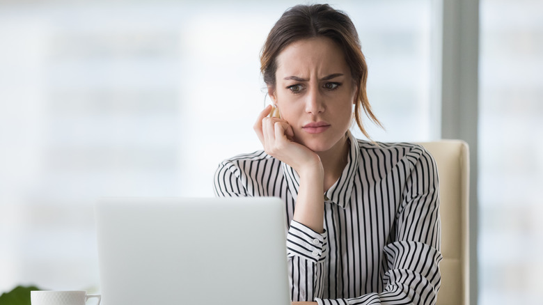 A concerned woman looking at her laptop screen