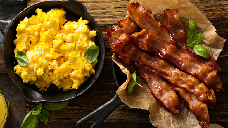 Scrambled eggs and bacon in skillets