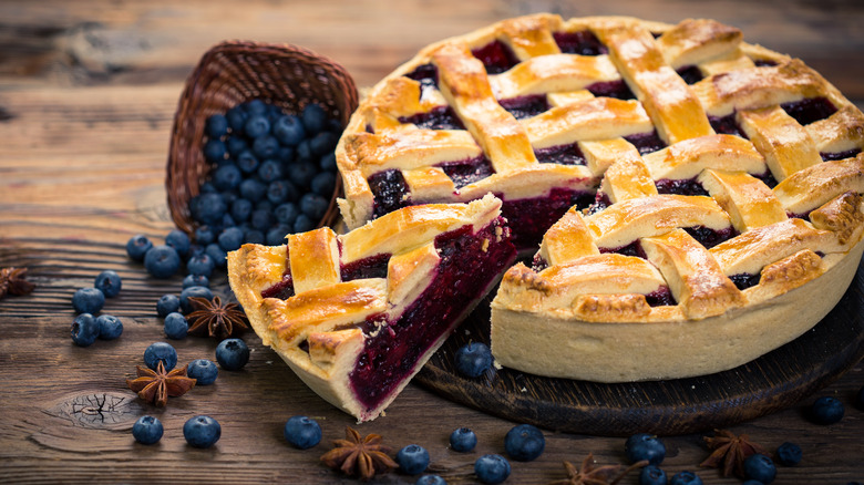 Blueberry pie with fresh blueberries on wooden surface