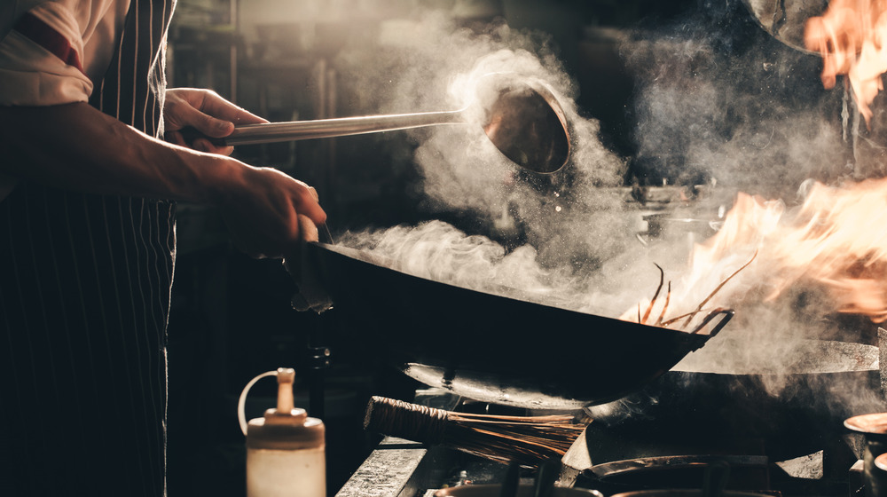 Chef using a steaming wok in a kitchen