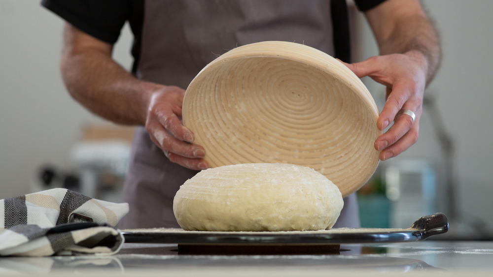 Man holding bowl over bread dough