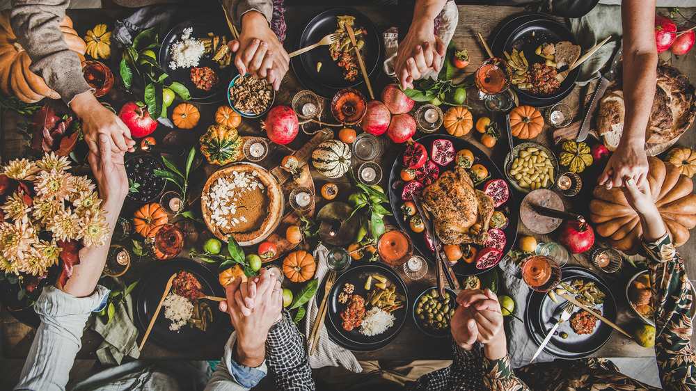 Thanksgiving table with turkey and sides, holding hands