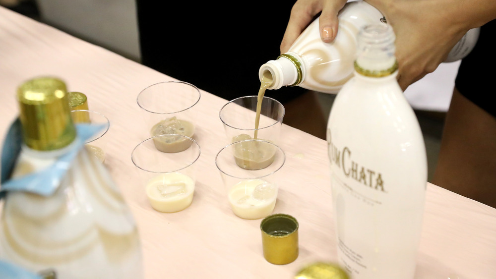 Hand pouring bottle of RumChata into taste cups