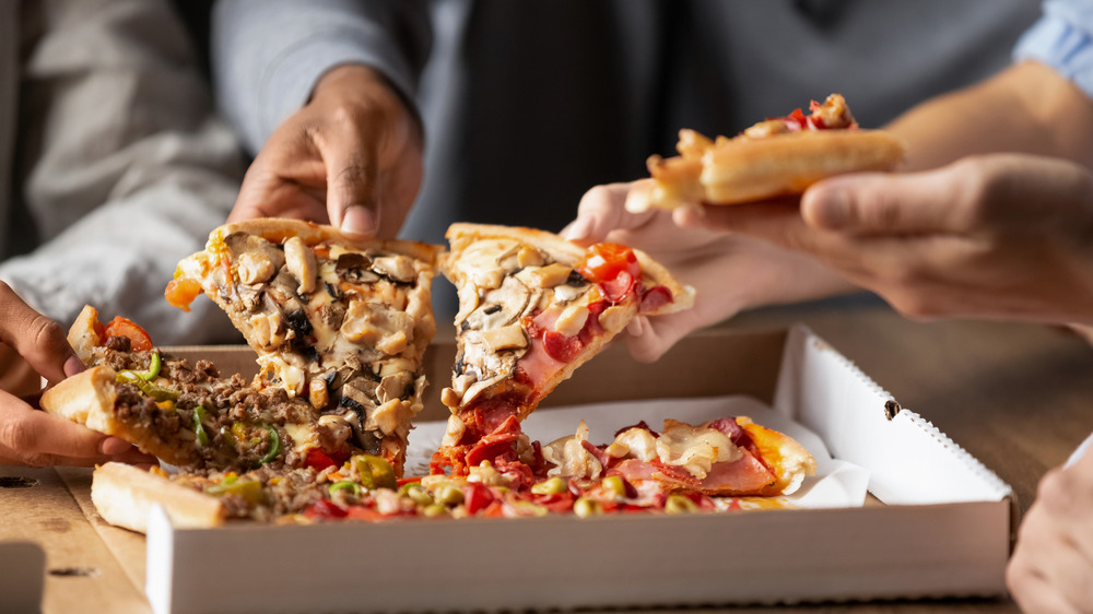 People eating pizza from a box