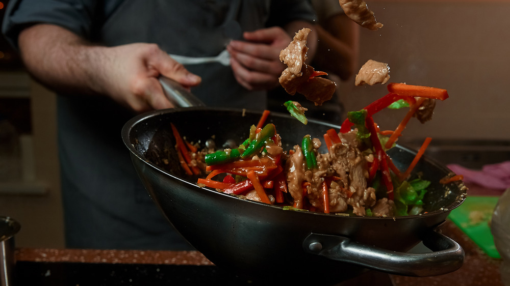 Tossing vegetables in a wok