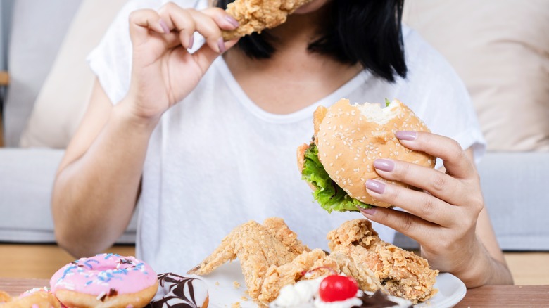 Woman eating fried chicken and donuts