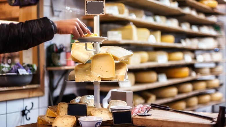 A hand grabs a sample from a cheese counter
