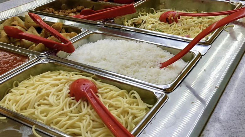 Buffet hot table with spaghetti and red utensils