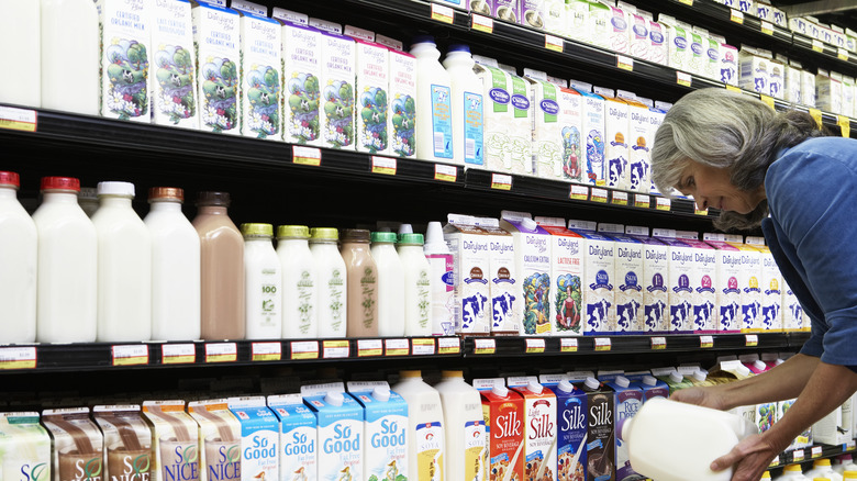 person taking milk from shelf