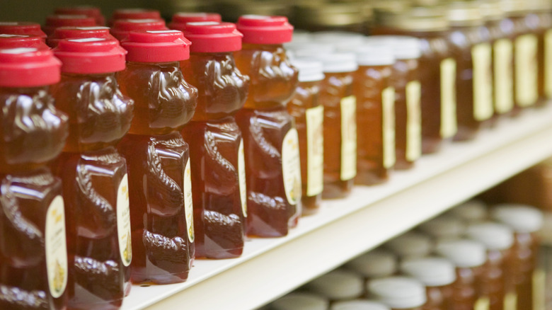 Plastic and glass bottles filled with honey on display in a grocery store aisle