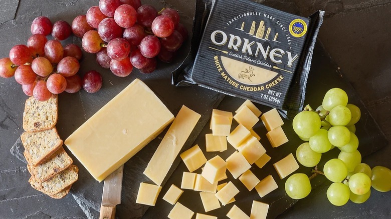 Trader Joe's Orkney cheese surrounded by two kinds of grapes, crackers, and cut cheese