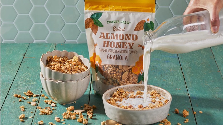 Person pouring milk into bowl of salted almond honey cereal with bag in the background.