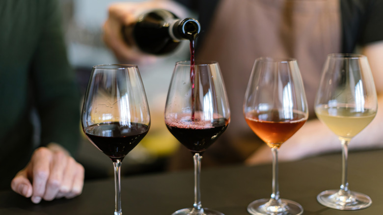 Variety of wines being poured into glasses.