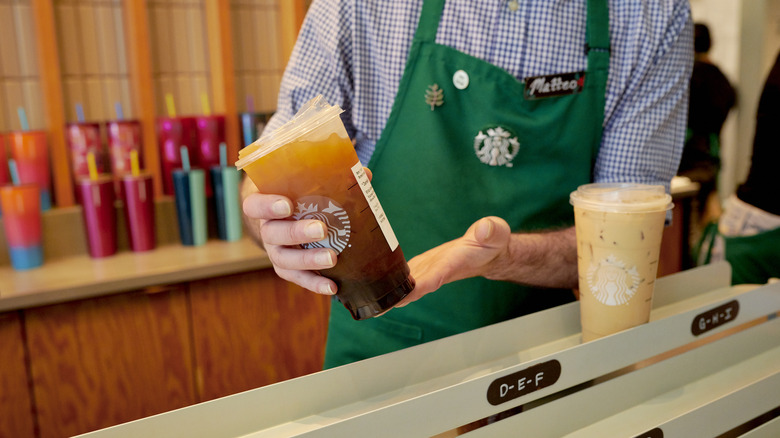 Starbucks employee holding iced drink