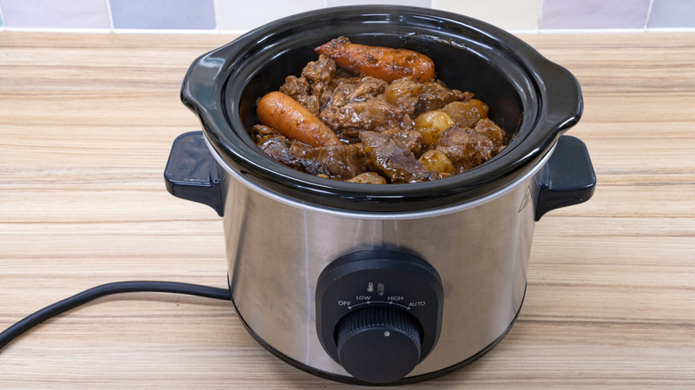 Small slow cooker with beef stew inside.