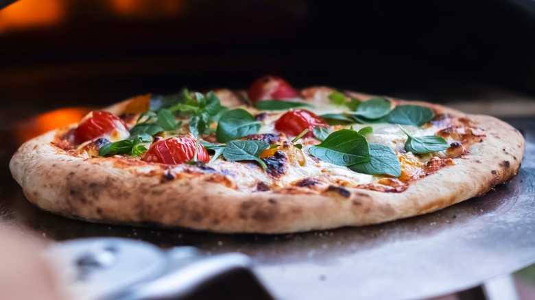 Pizza being pulled out of oven on pizza steel