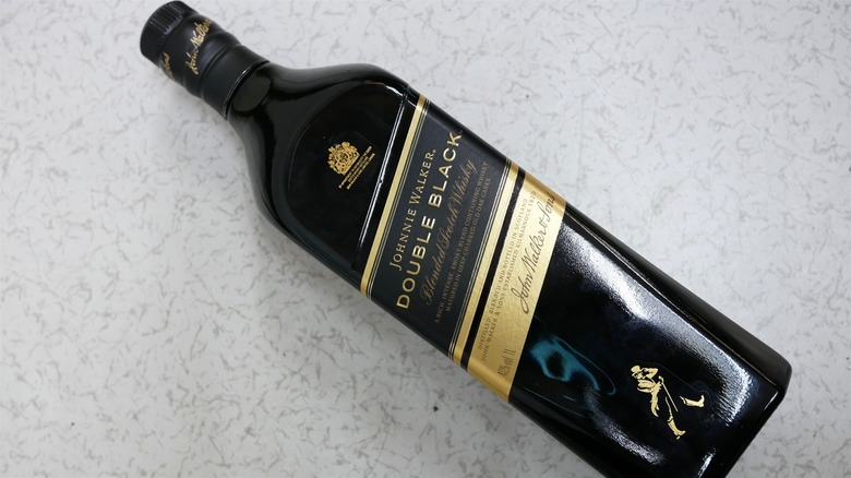 Bottle of Johnnie Walker Double Black laid flat on stone table.