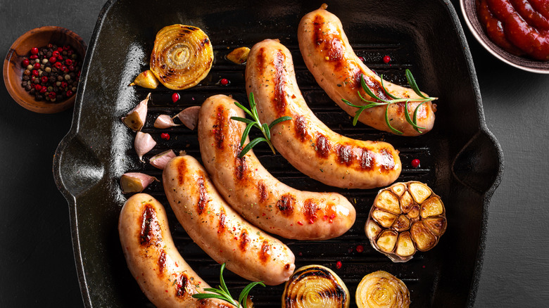 Cooked bratwurst in pan with garlic and onions