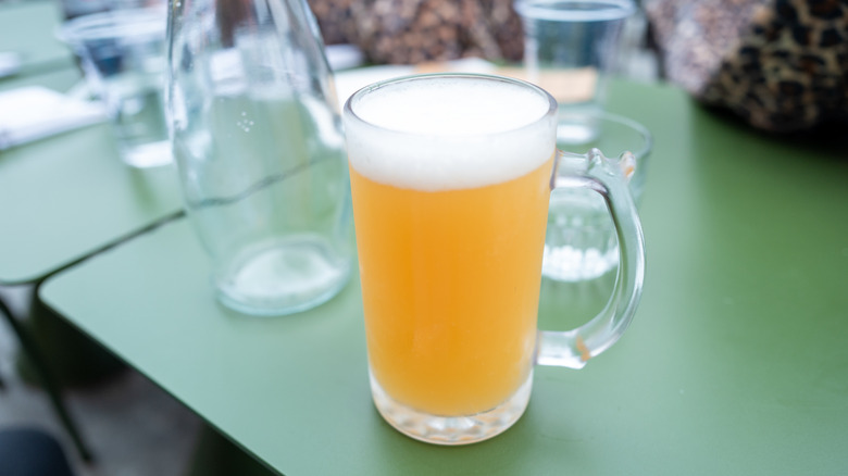 Pint of light beer on green restaurant table.