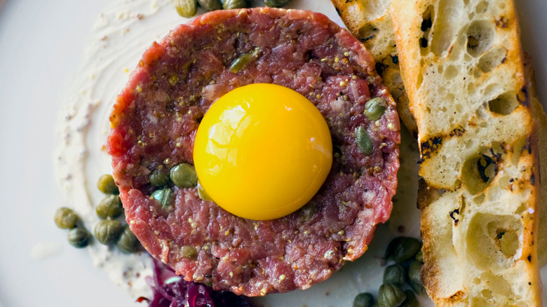 Steak tartare with egg yolk, capers, and bread