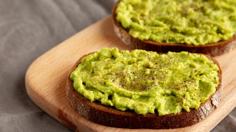 two slices of avocado toast on a cutting board