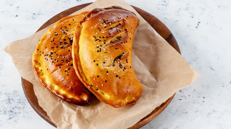 two pasties on a wooden plate