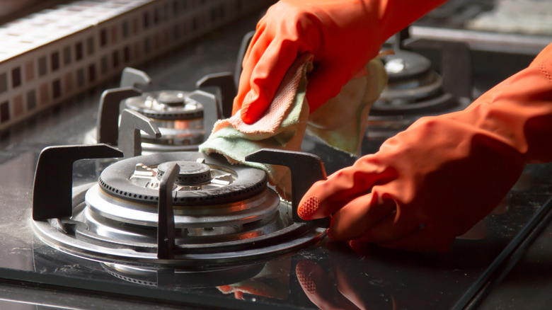 Gloved hands cleaning gas burner