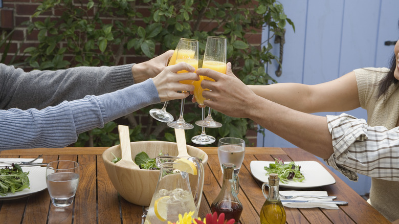 people clinking glasses of mimosas 