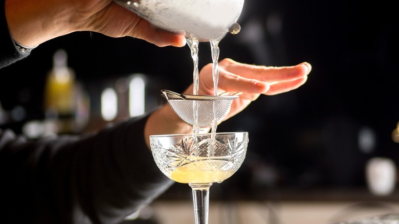 Bartender straining cocktail