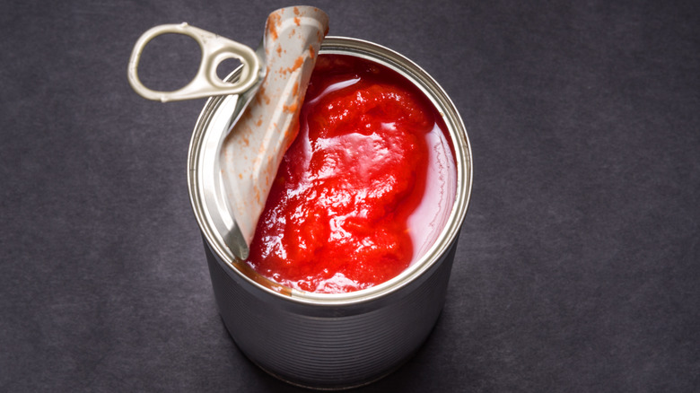 A can of tomatoes on a black background from above