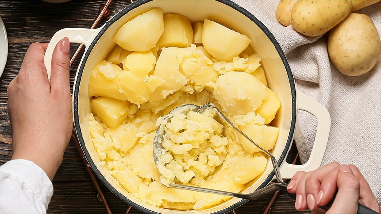 Person mashing potatoes in pot