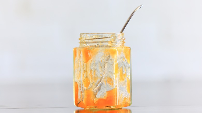 empty jar of orange jam with silver spoon inside