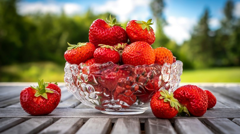 Bunch of strawberries in a glass bowl on wooden table