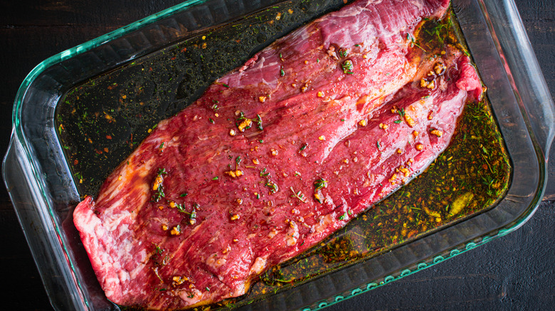 raw steak marinating in baking dish