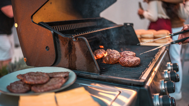 American cheese on a tray next a grill where burgers are being cooked